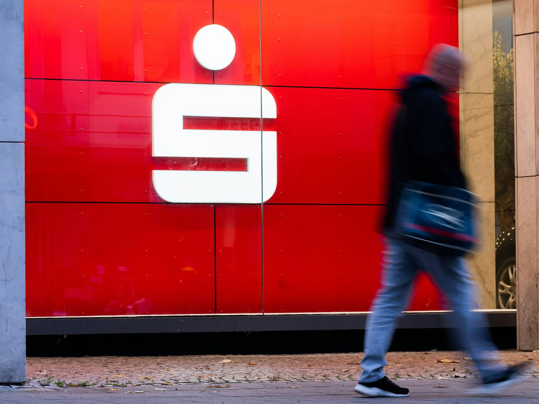 Ein Fußgänger läuft an einer Filiale der Sparkasse vorbei. Ein beliebter Service wird in Kürze abgeschafft.