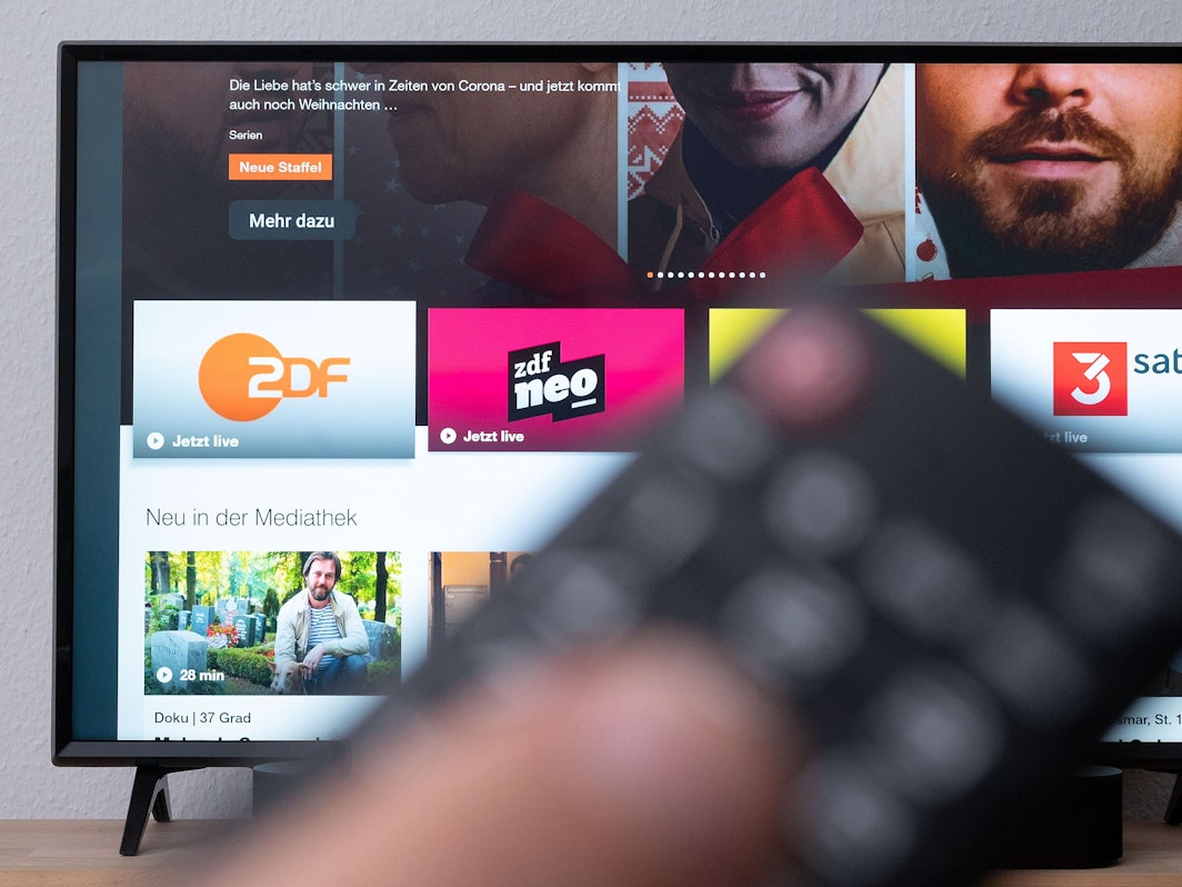 Ein Mann hält eine Fernbedienung vor einen Fernseher, auf dem die ZDF-Mediathek zu sehen ist