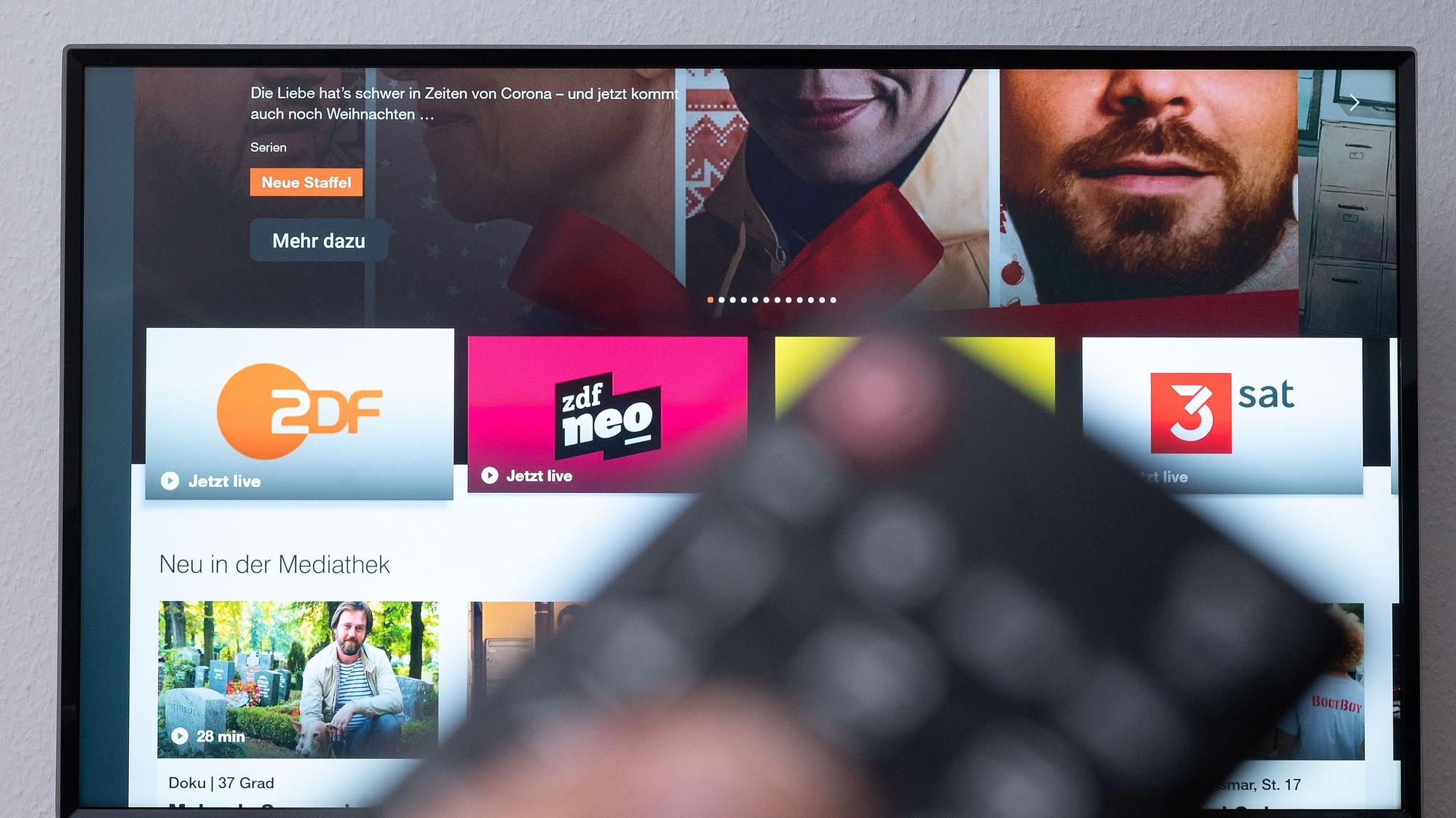 Ein Mann hält eine Fernbedienung vor einen Fernseher, auf dem die ZDF-Mediathek zu sehen ist