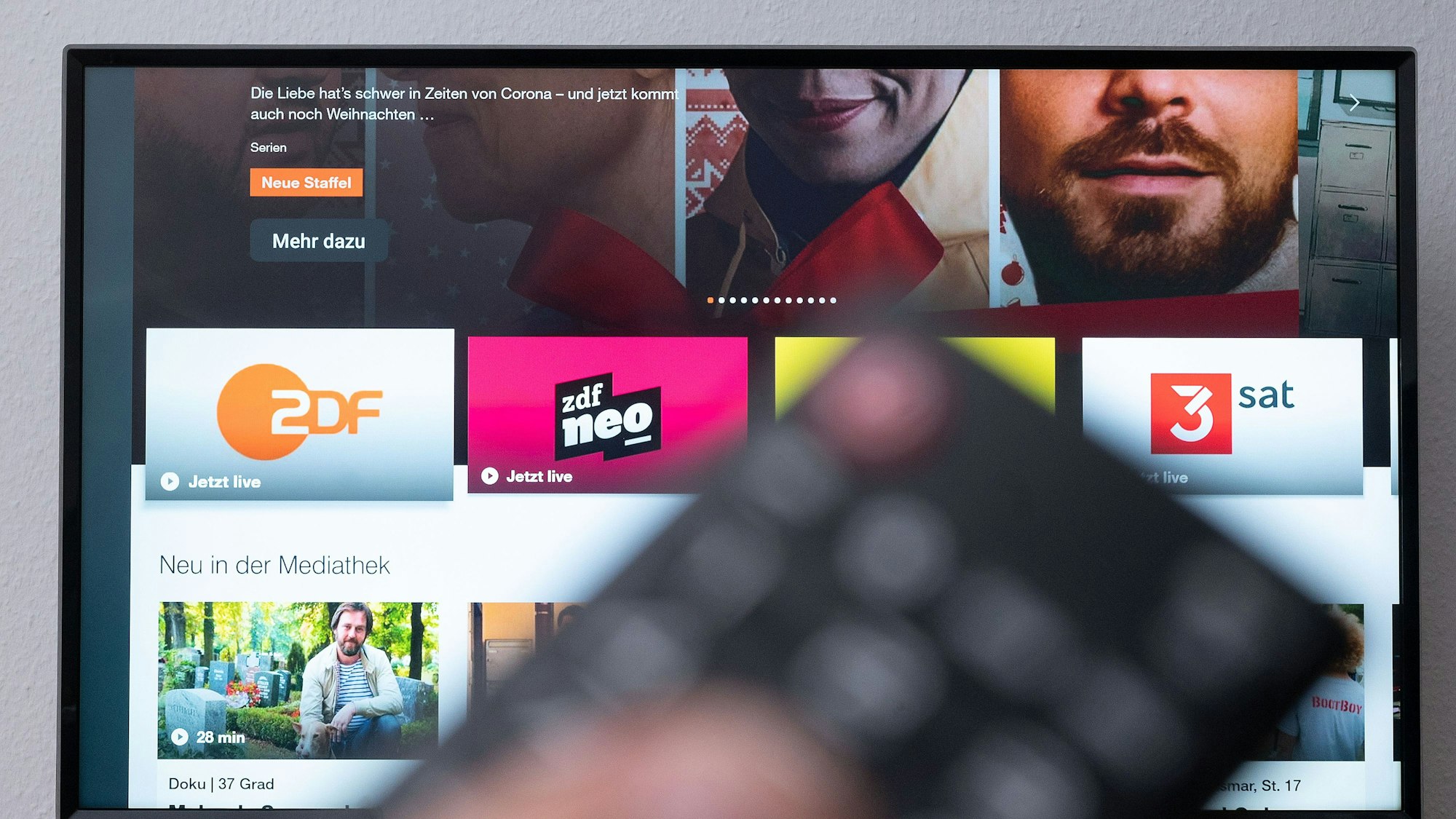 Ein Mann hält eine Fernbedienung vor einen Fernseher, auf dem die ZDF-Mediathek zu sehen ist