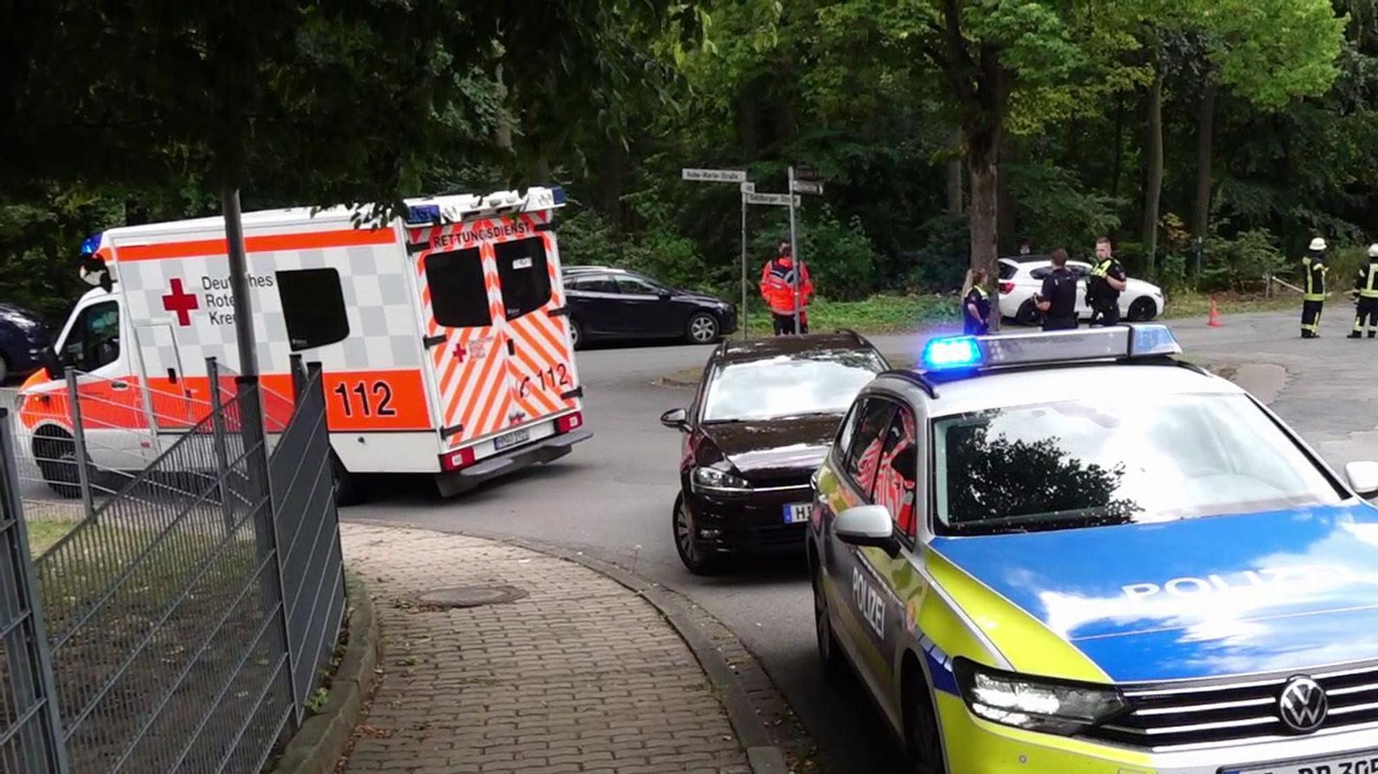 Ein Polizeifahrzeug und ein Krankenwagen stehen an einer Unfallstelle. In Köln-Müngersdorf kam es zu einer Kollision zwischen einem Roller und einem Kleinwagen, der Rollerfahrer wurde schwer verletzt.
