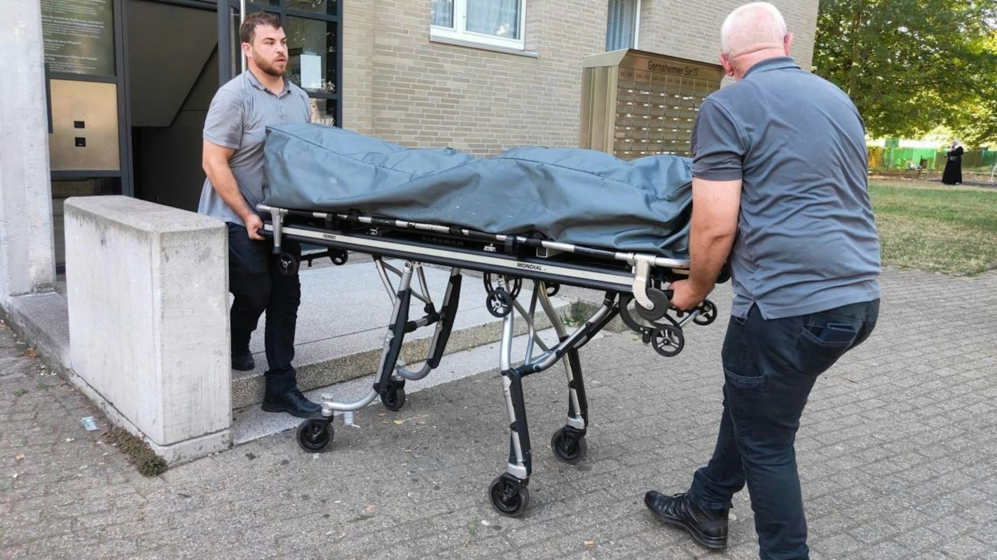 Zwei Bestatter rollen den Leichnam von Louzef B. auf einer Bahre aus dem Wohnhaus.