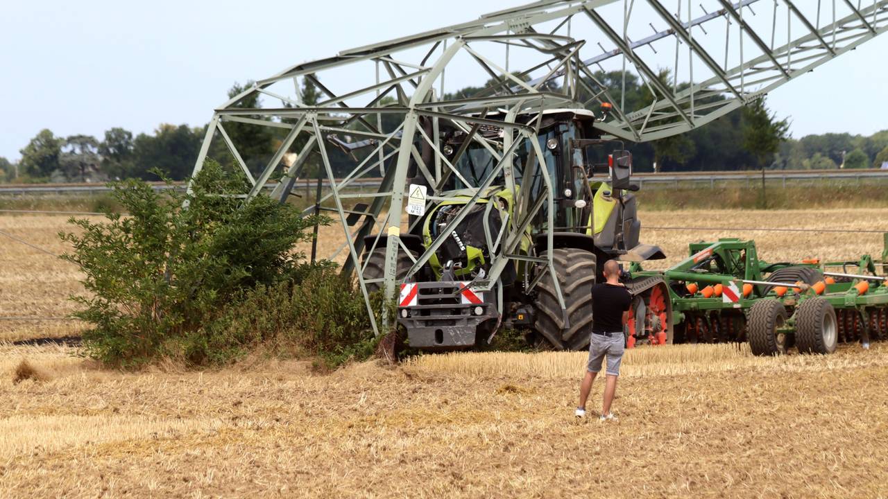 Ein Traktor steht auf einem Feld unter einem umgeknickten Strommast.