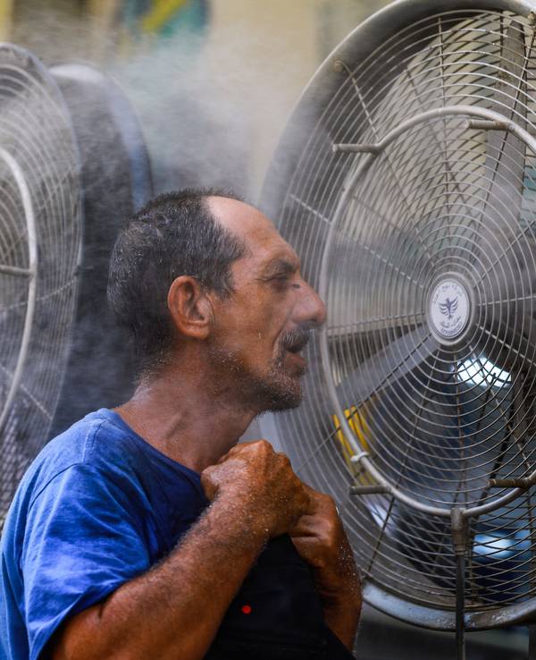 Ein Mann kühlt sich vor einem Ventilator ab, während im Irak eine Hitzewelle herrscht