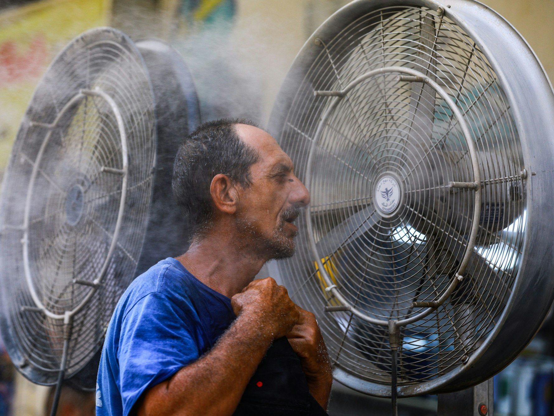 Das Symbolfoto aus dem Jahr 2022 zeigt einen Mann, der sich wegen der herrschenden Hitze direkt vor einen Ventilator stellt.