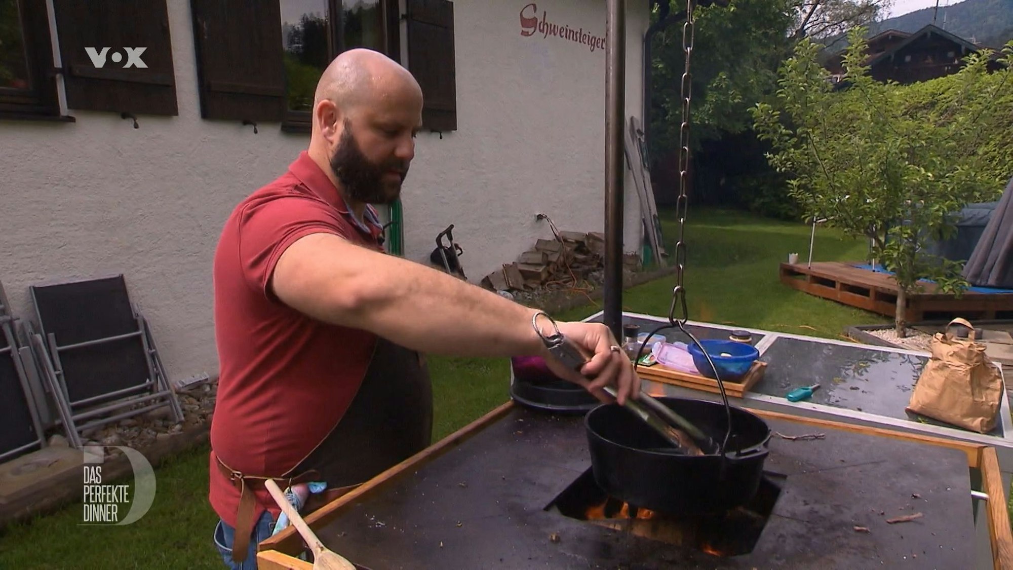 Robert fuchtelt mit einer Grillzange über dem offenen Feuer herum.