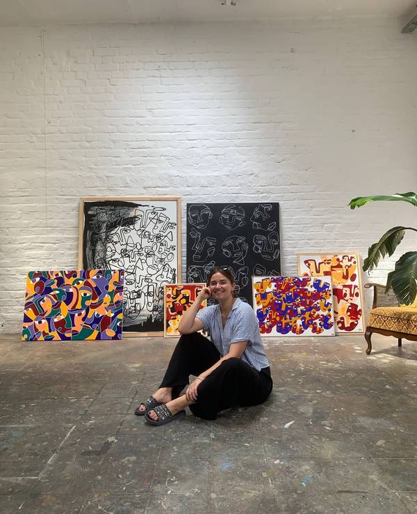 Hanna Hodler sitzt in ihrem Atelier auf dem Boden vor einigen ihrer Bilder.