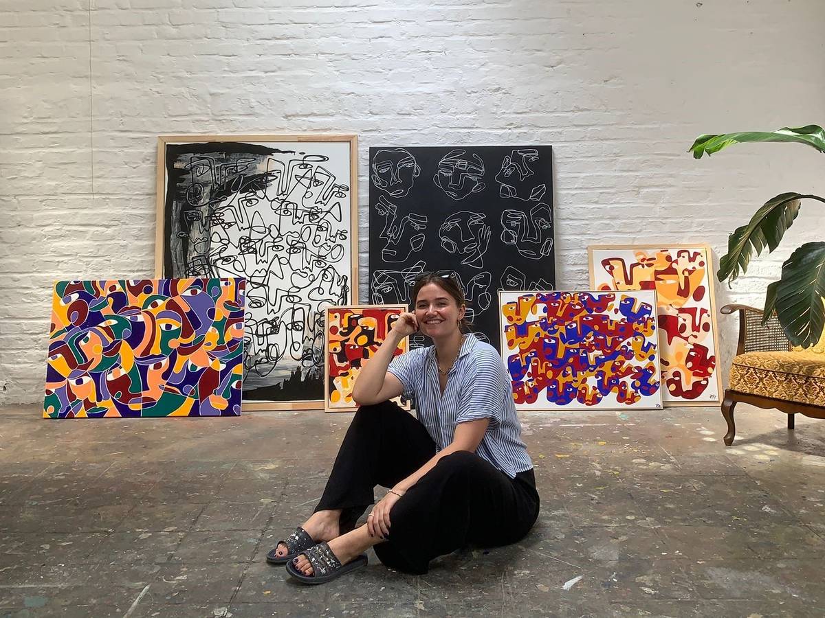 Hanna Hodler sitzt in ihrem Atelier auf dem Boden vor einigen ihrer Bilder.