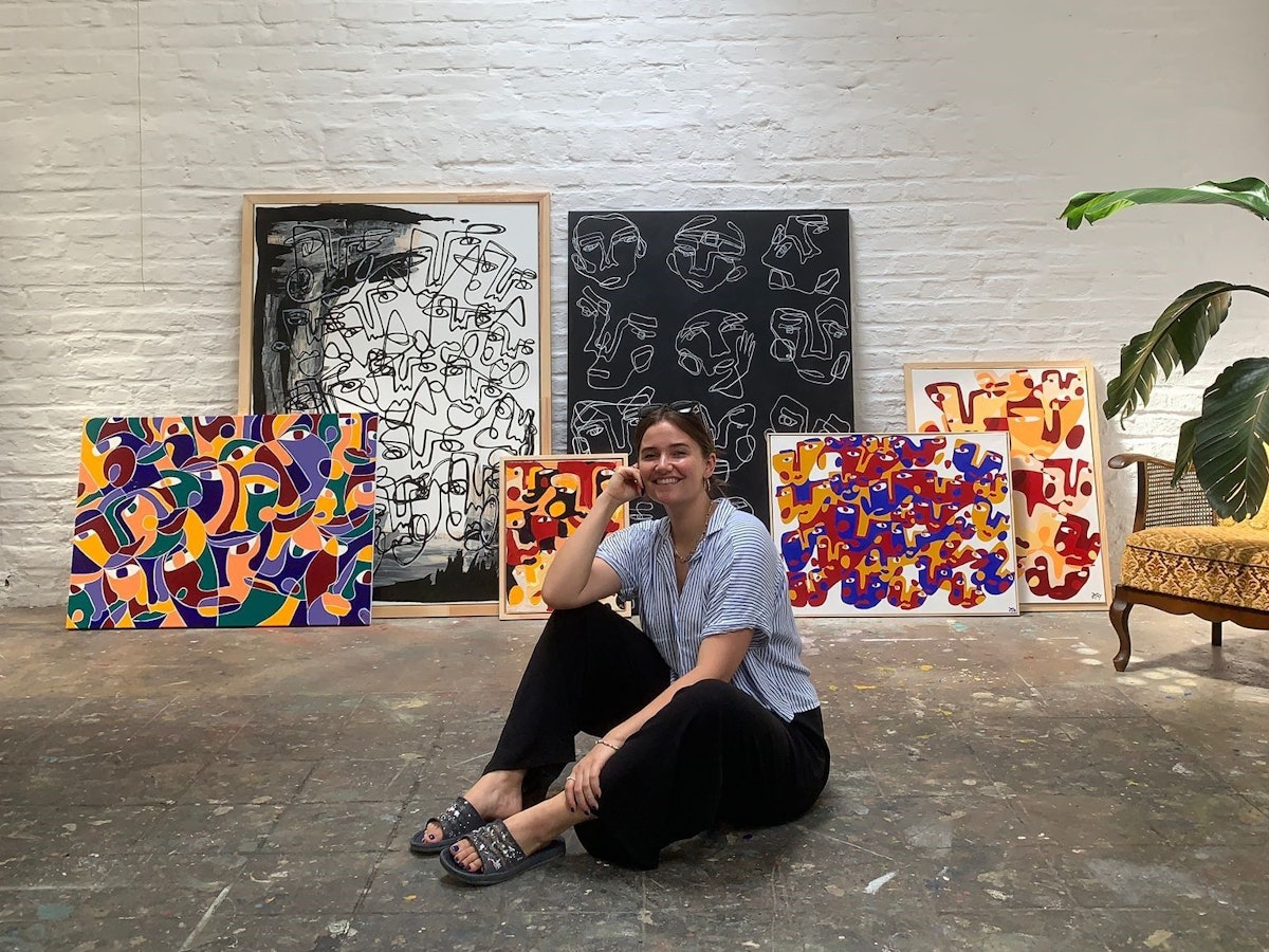 Hanna Hodler sitzt in ihrem Atelier auf dem Boden vor einigen ihrer Bilder.