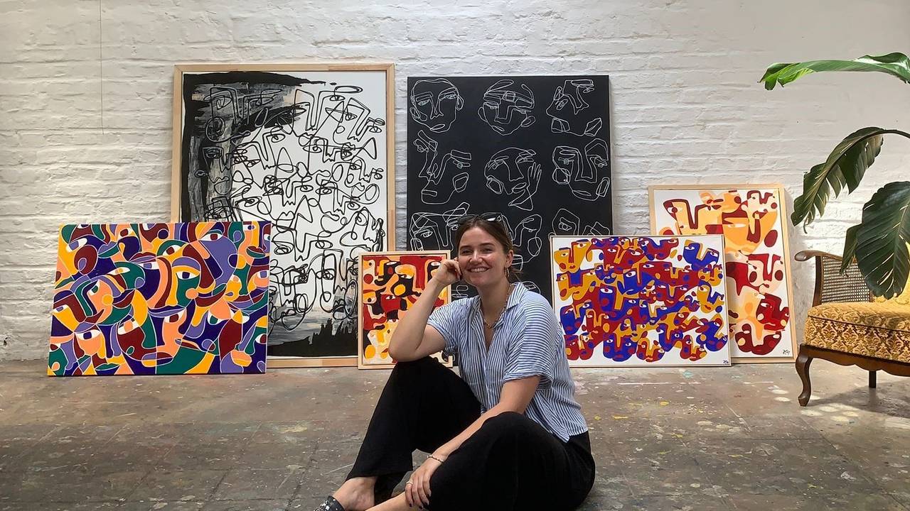 Hanna Hodler sitzt in ihrem Atelier auf dem Boden vor einigen ihrer Bilder.
