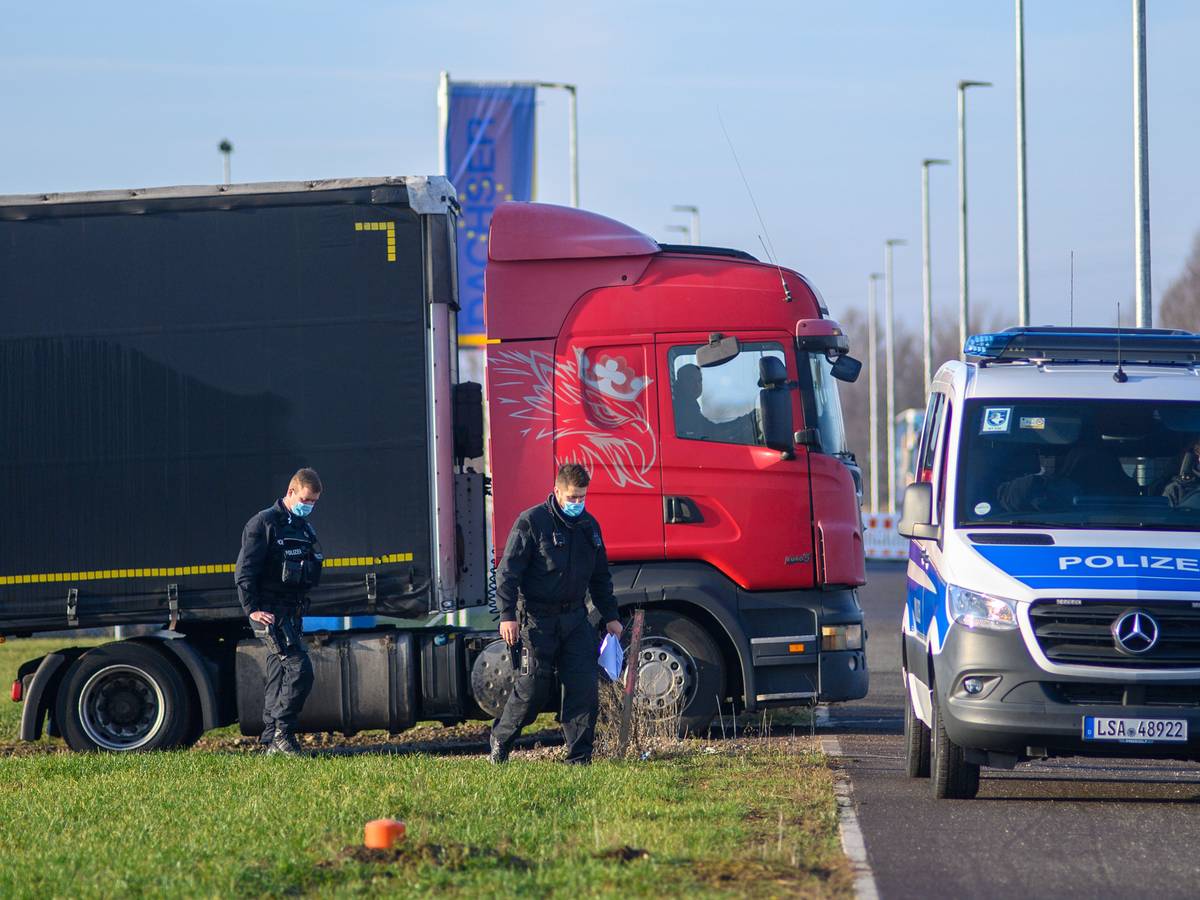 Polizisten gehen zu ihrem Fahrzeug während dahinter ein Lastwagen seinen Stellplatz verlässt.