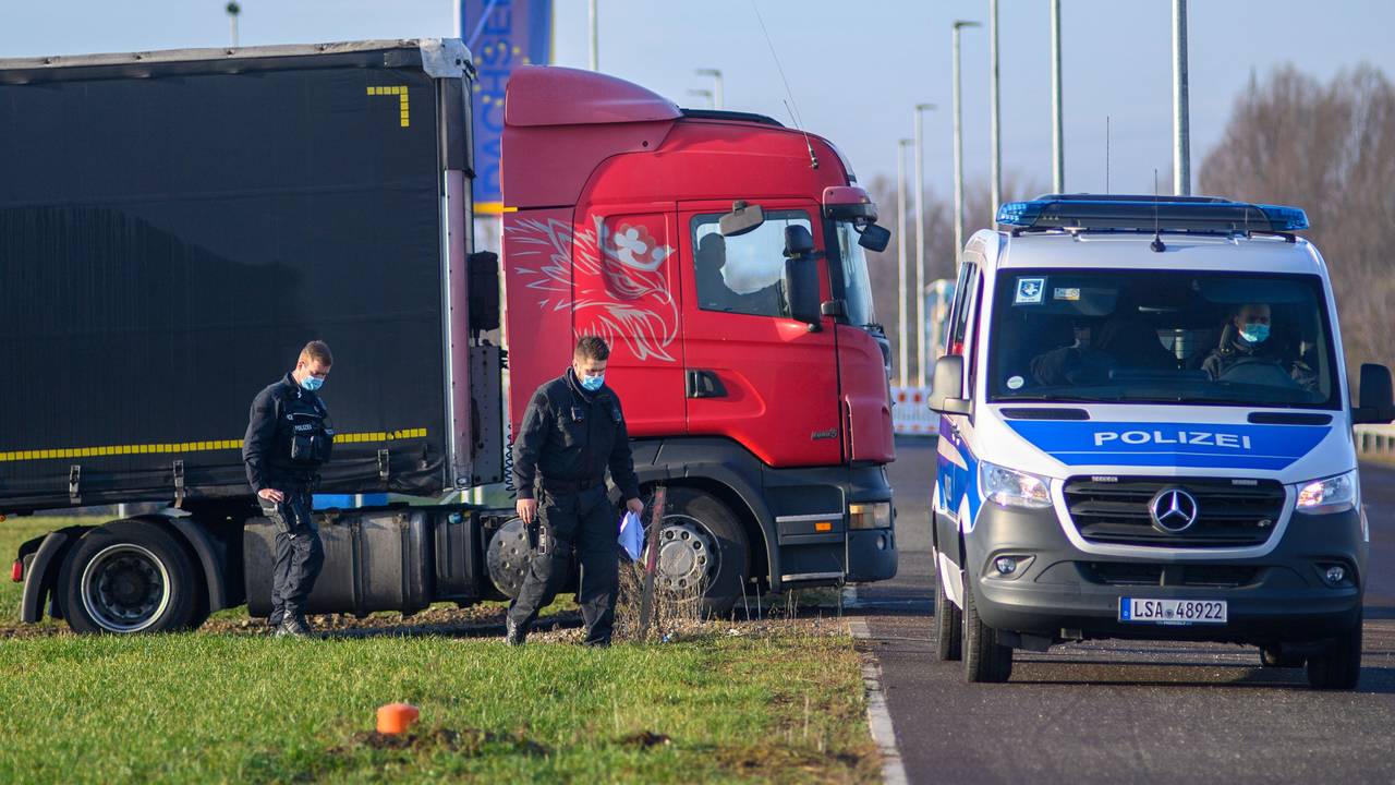 Polizisten gehen zu ihrem Fahrzeug während dahinter ein Lastwagen seinen Stellplatz verlässt.