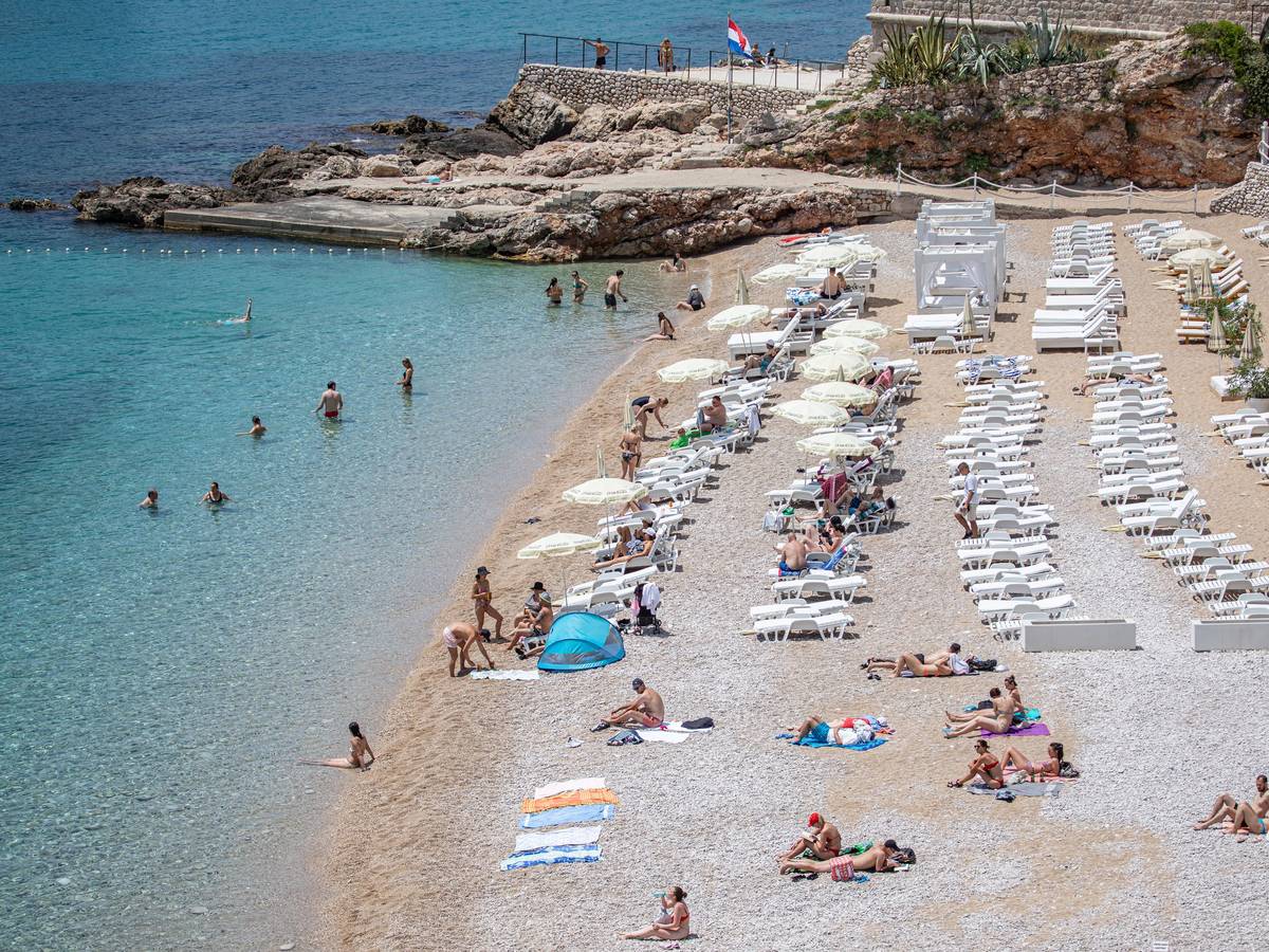 Touristinnen und Touristen entspannen am Strand von Dubrovnik (Kroatien).