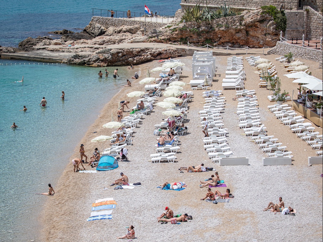 Touristinnen und Touristen entspannen am Strand von Dubrovnik (Kroatien).