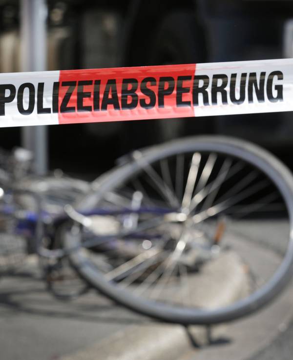 Demoliertes Fahrrad liegt auf einer Straße, davor ein Absperrband der Polizei.