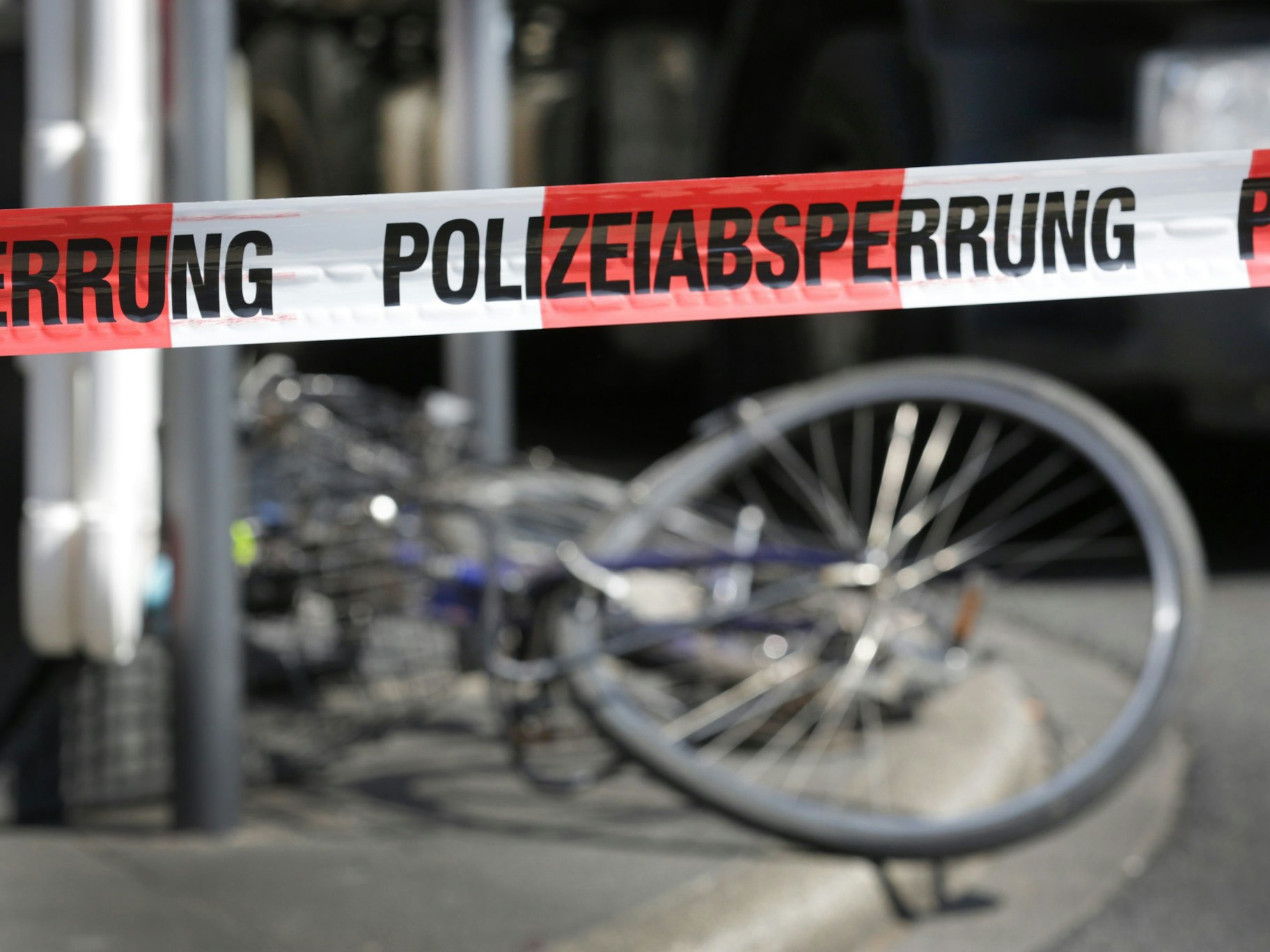 Demoliertes Fahrrad liegt auf einer Straße, davor ein Absperrband der Polizei.