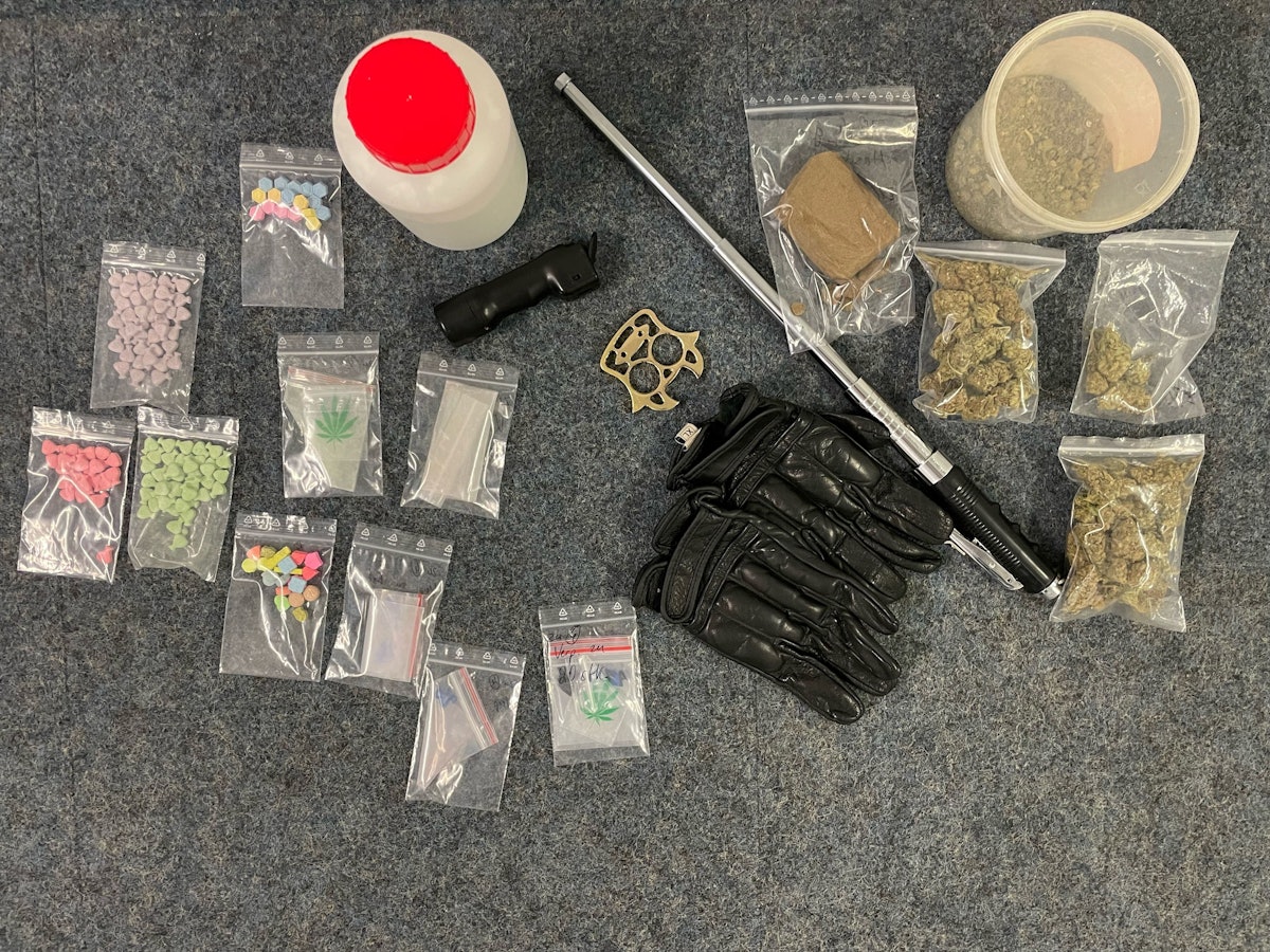 In kleinen Tütchen befinden sich diverse Drogen, dazwischen liegen Waffen wie ein Teleskopschlagstock.