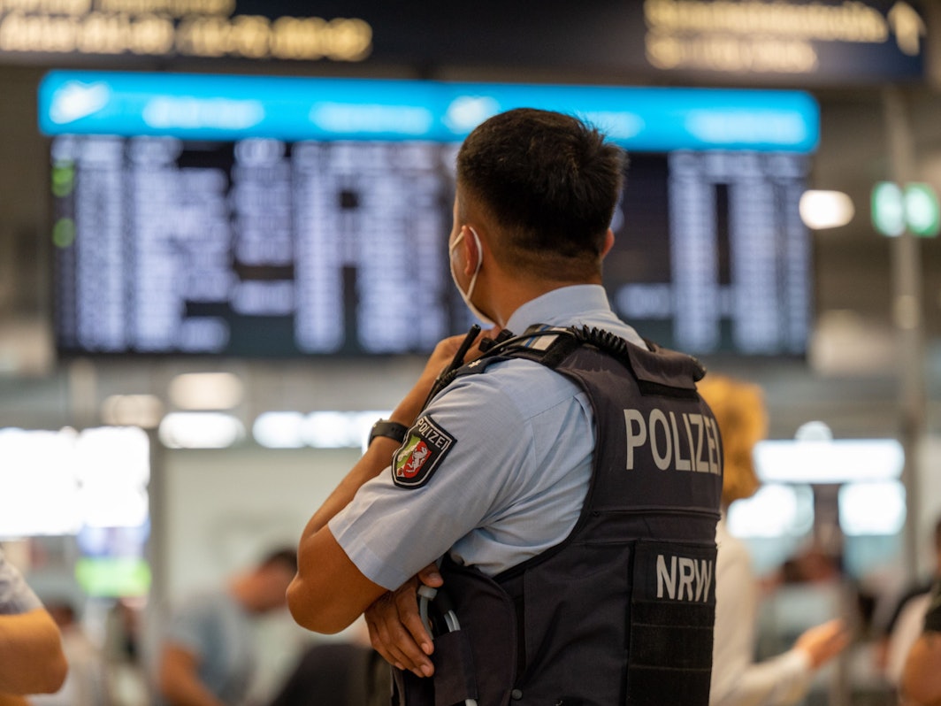 Ein Bundespolizist steht vor einer Anzeigetafel im Flughafen Köln/Bonn.
