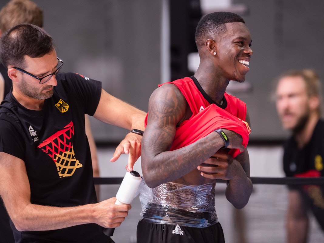 Dennis Schröder (r) lässt sich nach dem Training der Basketball-Nationalmannschaft einen Eisbeutel am Rücken befestigen. Die Mannschaft bereitet sich auf die Europameisterschaft vor, die im September ausgetragen wird.