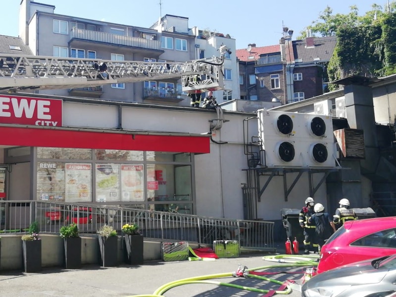 Einsatzkräfte der Feuerwehr löschen den Brand in einem Rewe-Markt in der Kölner Südstadt.