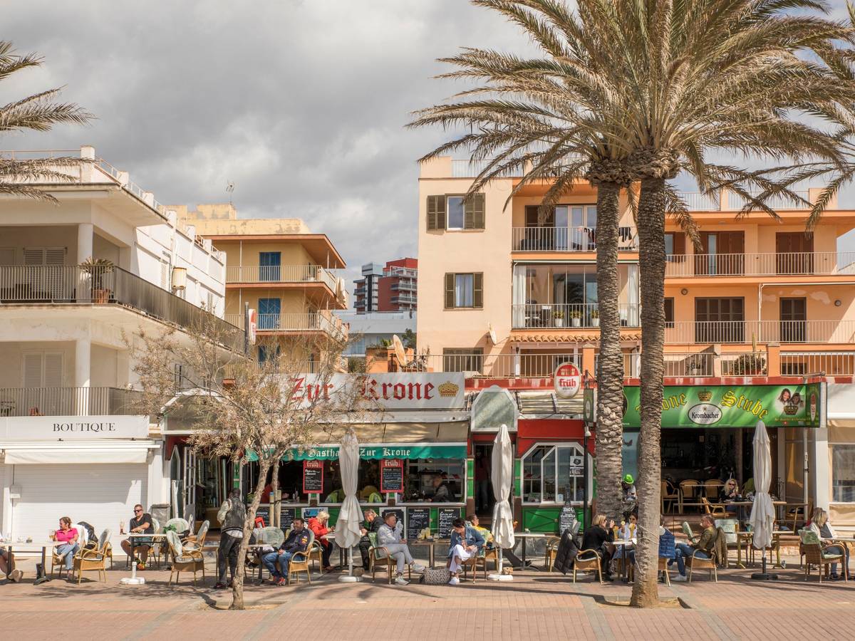 Deutsche Touristen sitzen in der bekannten Bar Zur Krone & Krone Stube und genießen einen Drink in der Sonne an der Playa de Palma auf Mallorca.