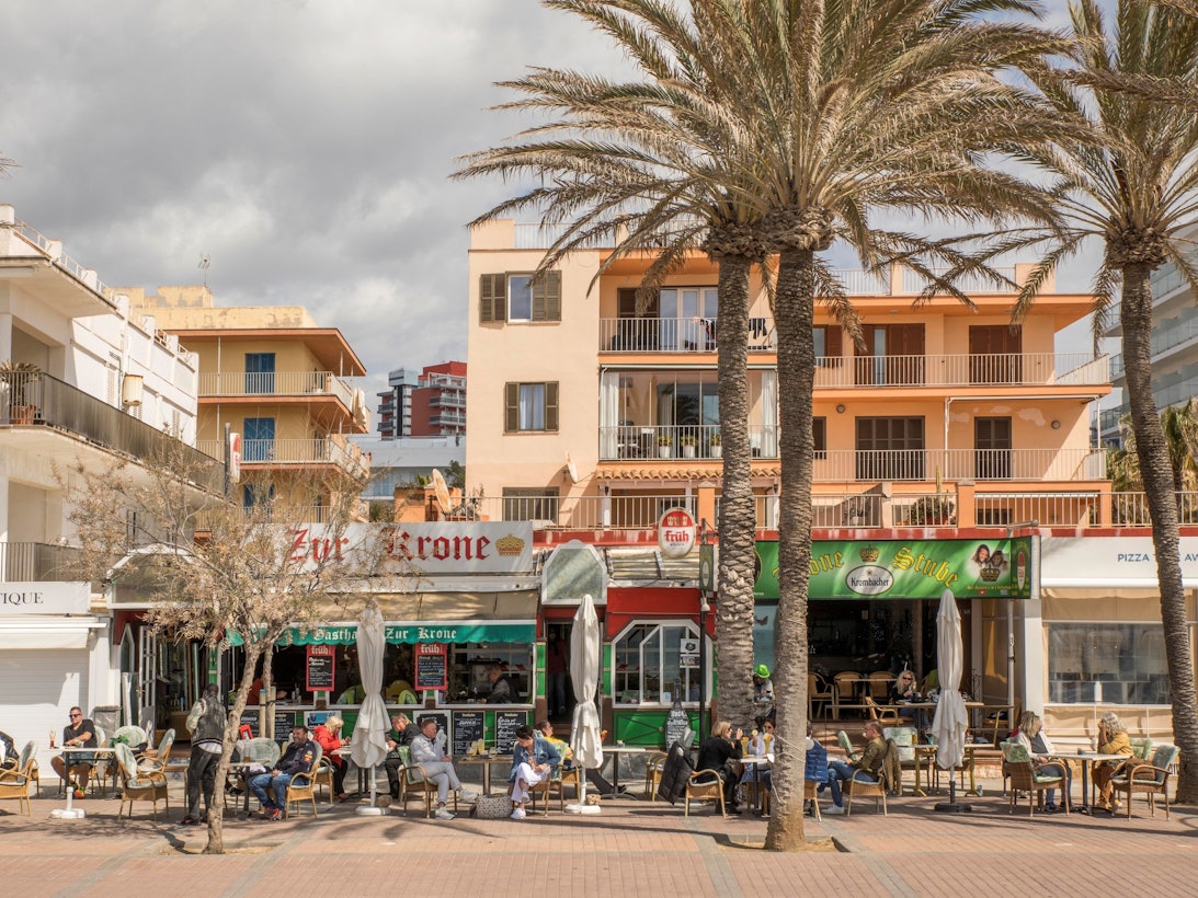 Deutsche Touristen sitzen in der bekannten Bar Zur Krone & Krone Stube und genießen einen Drink in der Sonne an der Playa de Palma auf Mallorca.