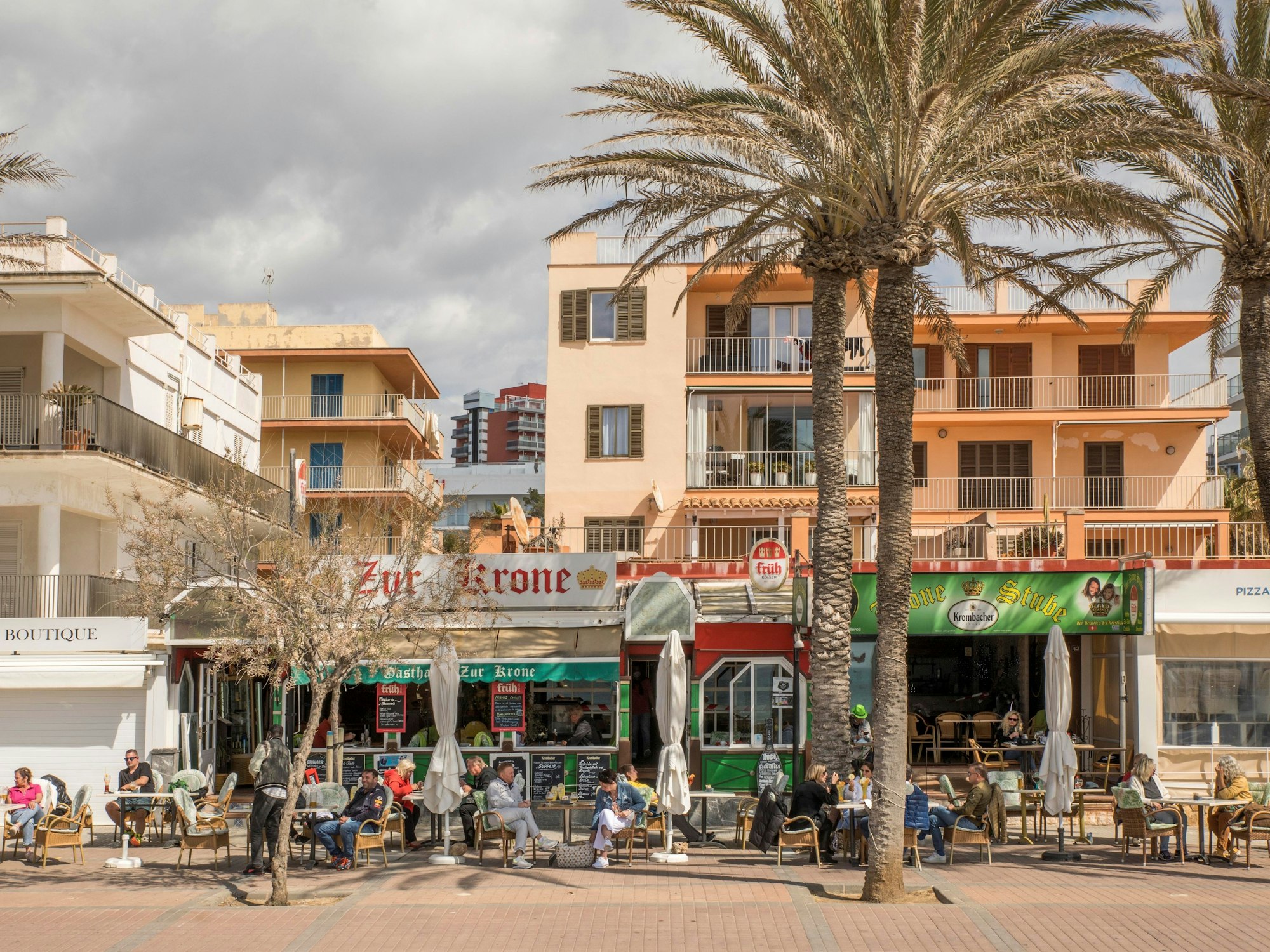 Deutsche Touristen sitzen in der bekannten Bar Zur Krone & Krone Stube und genießen einen Drink in der Sonne an der Playa de Palma auf Mallorca.
