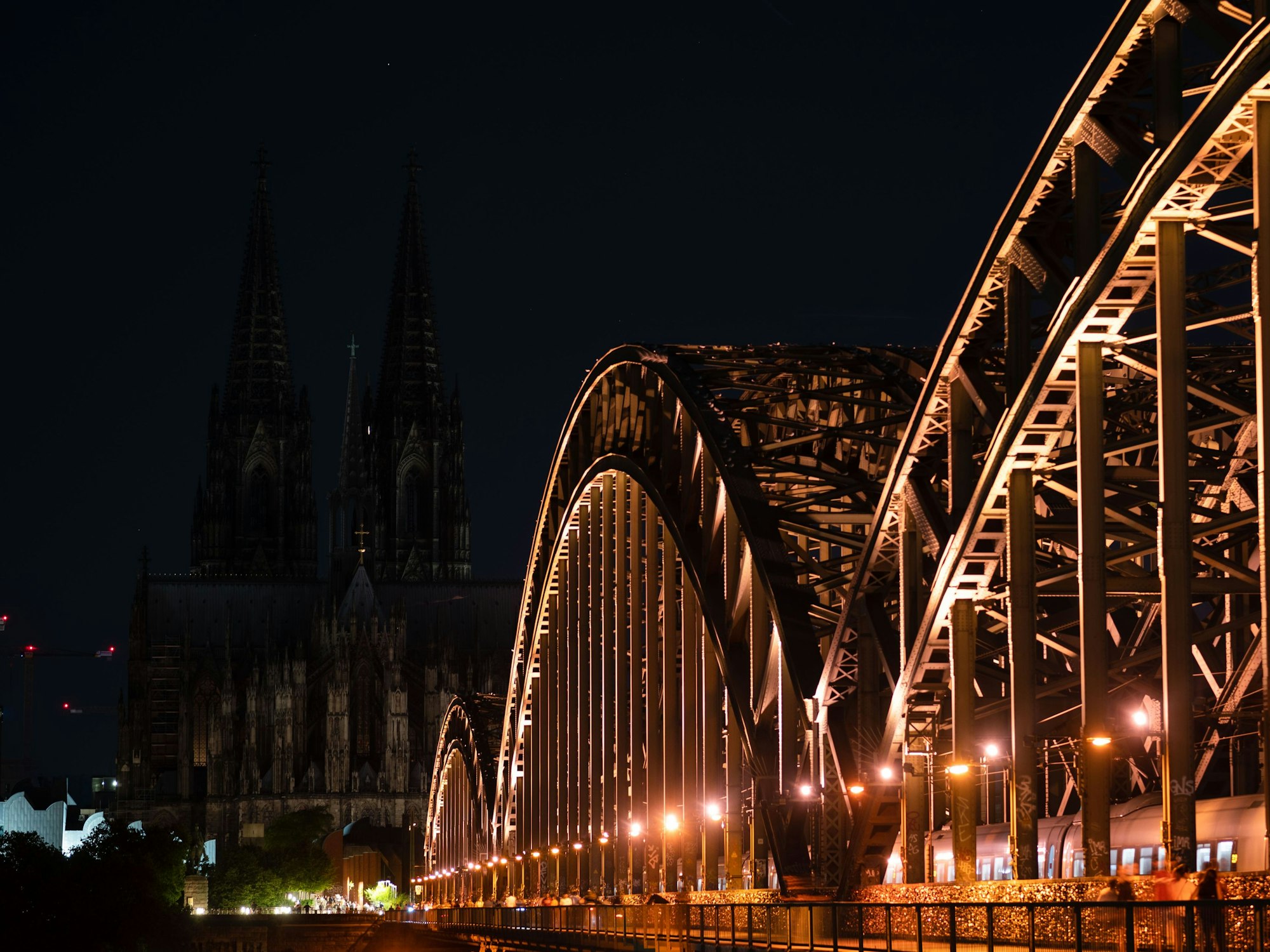Unbeleuchtet ist der Kölner Dom nach 23 Uhr. Im Vordergrund die Hohenzollernbrücke.
