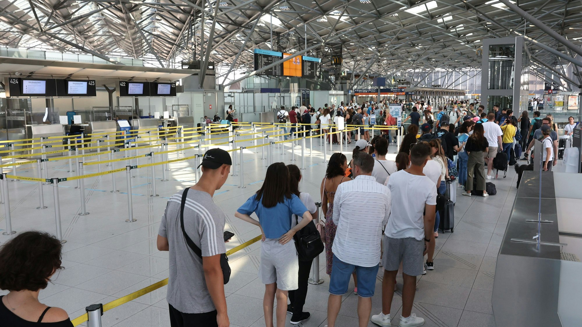Menschen stehen am Flughafen vor der Sicherheitskontrolle Schlange.