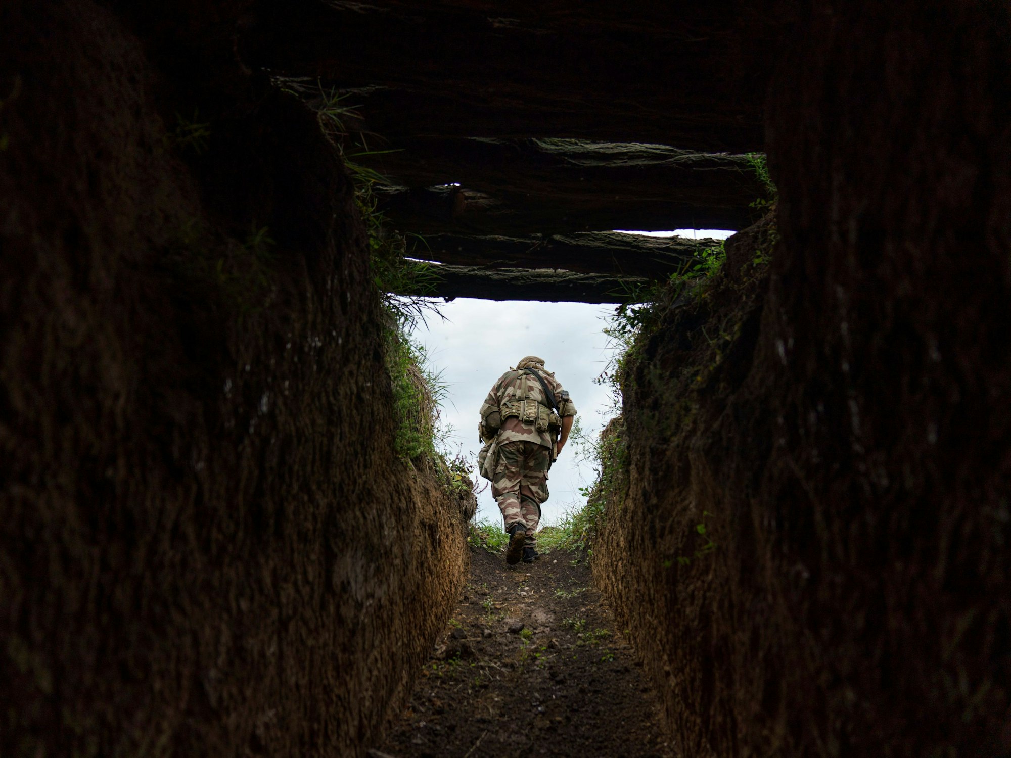 05.08.2022, Ukraine, Slowjansk: Oberstabsfeldwebel Artur Shevtsov vom Regiment Dnipro-1 verlässt einen Bunker in der Stellung der Einheit in der Nähe von Slowjansk in der Region Donezk in der Ostukraine. Von einer Stellung am Stadtrand aus bauen Soldaten des Regiments Dnipro-1 ein Netz von Schützengräben aus und graben Bunker, die die Soldaten vor Mörsereinschlägen und Phosphorbomben schützen sollen. Foto: David Goldman/AP/dpa +++ dpa-Bildfunk +++