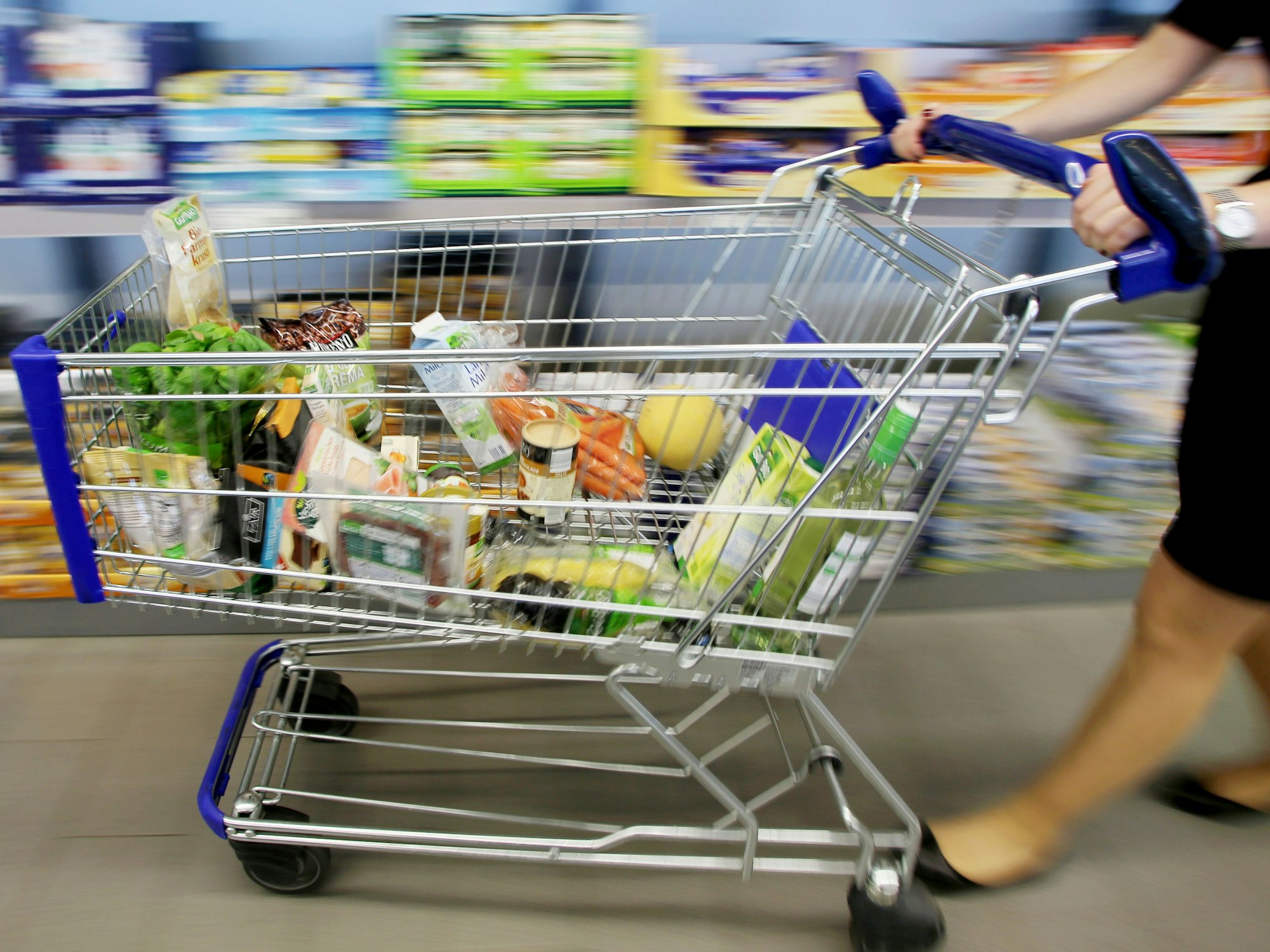 Eine Frau schiebt einen gefüllten Einkaufswagen.