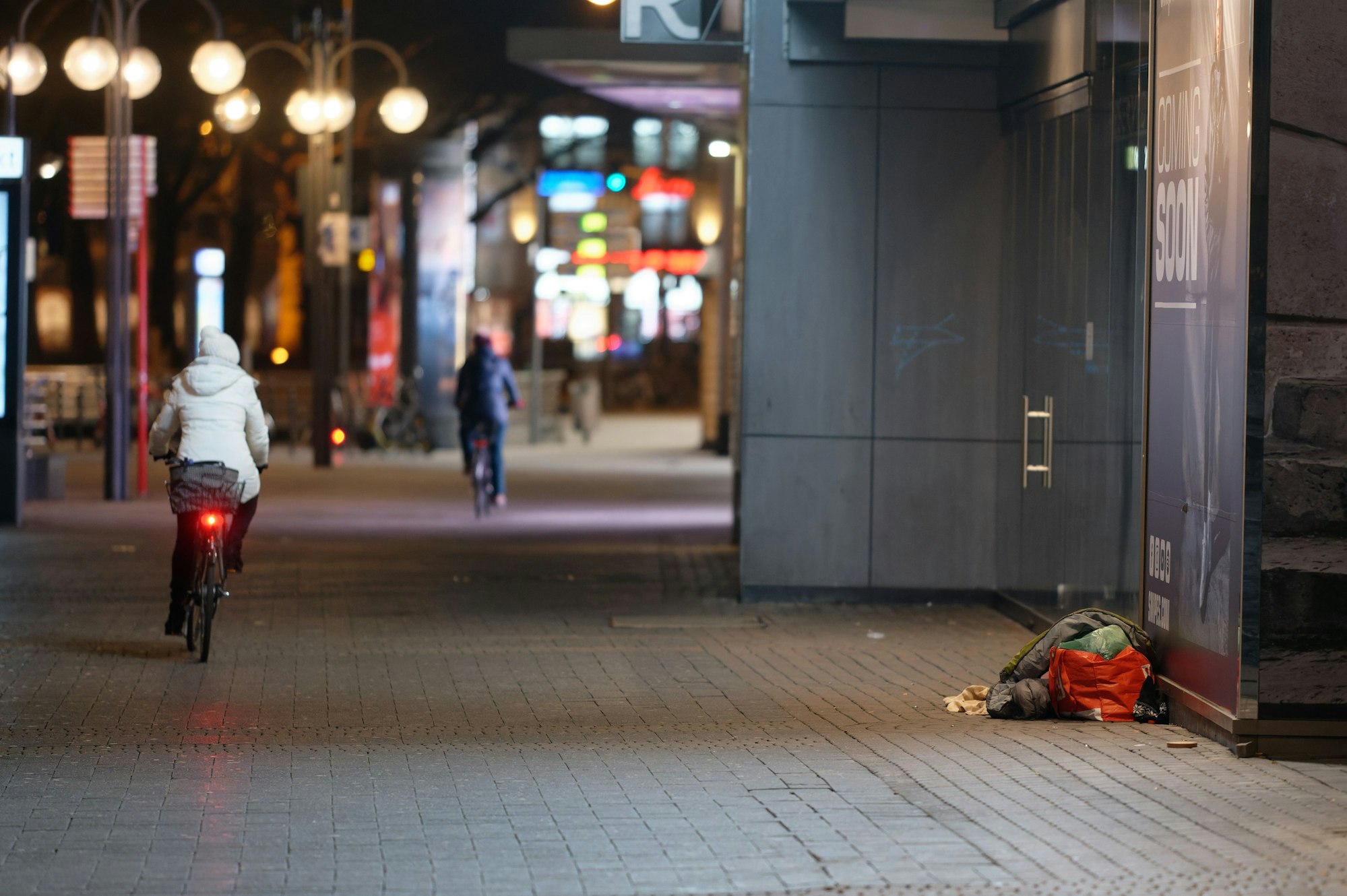 Ein Mensch liegt in der Innenstadt in einem Schlafsack im Eingang zu einem Geschäft.