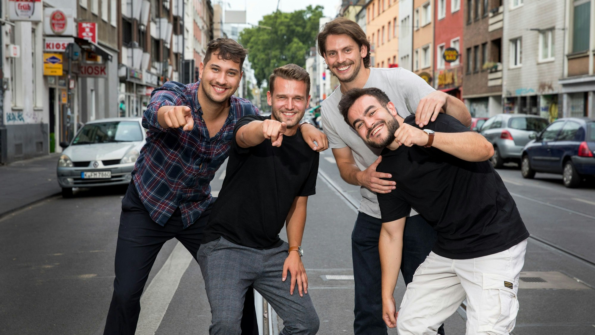 Vier Studenten stehen auf der Zülpicher Straße und deuten in die Kamera. Sie alle sind Teil von Malle Anja, die Band hat jetzt einen Mallorca-Hit.