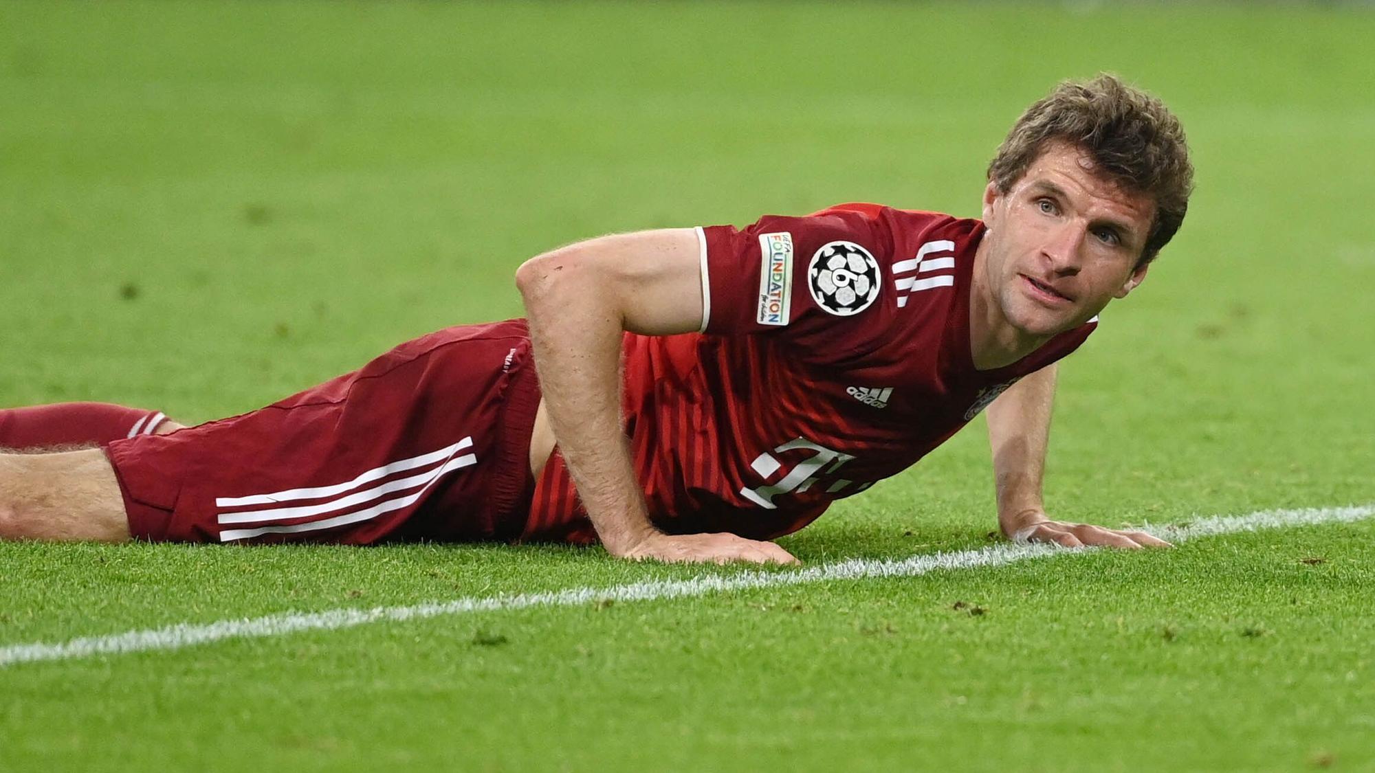 Thomas Müller stützt sich mit beiden Händen auf dem Rasen ab.