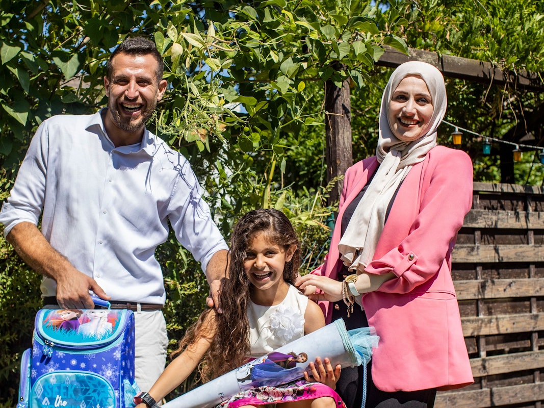 Angela, sechs Jahre alt und frisch eingeschult, strahlt mit Vater Ezzat und Mutter Medea um die Wette.