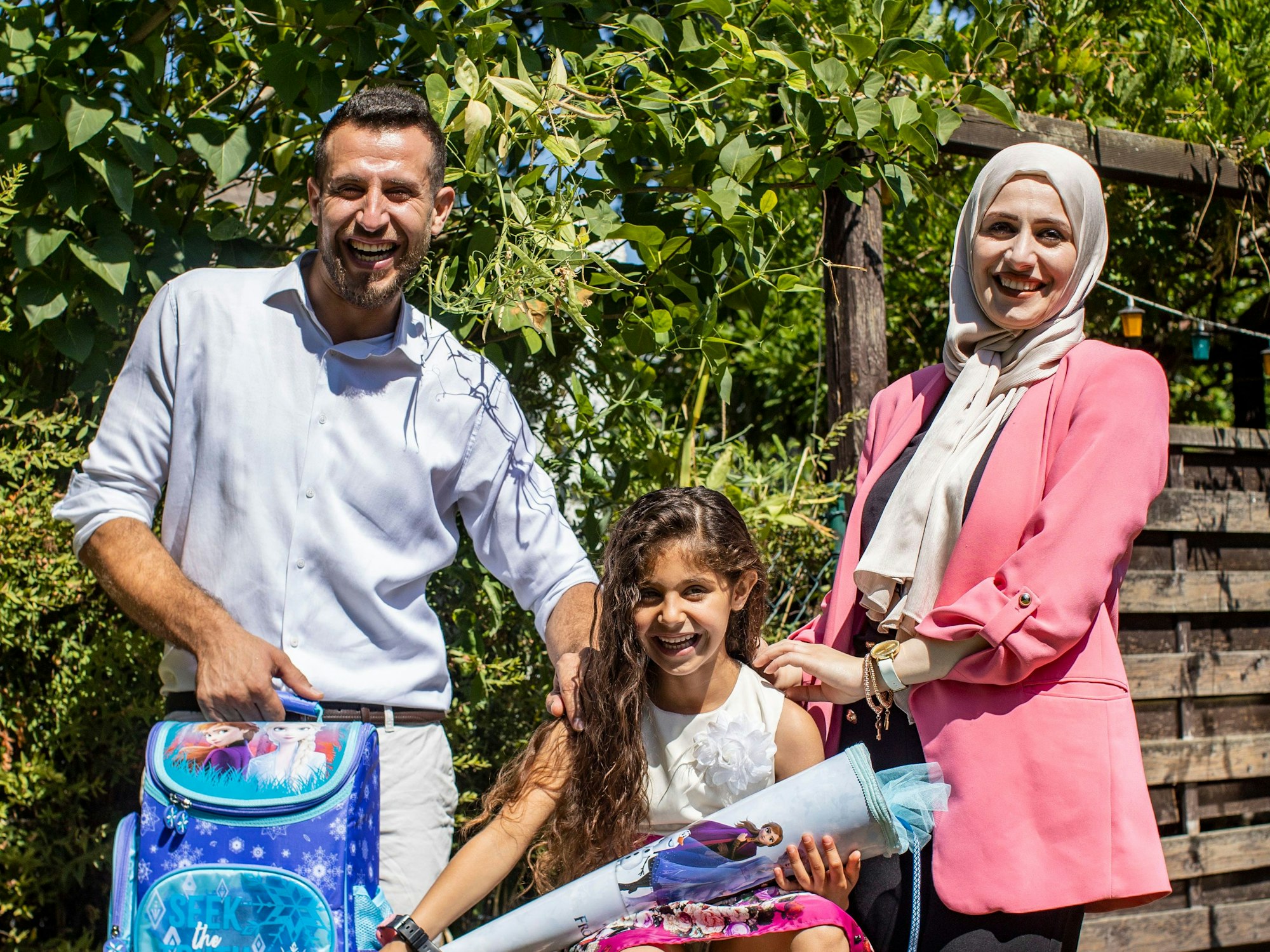 Angela, sechs Jahre alt und frisch eingeschult, strahlt mit Vater Ezzat und Mutter Medea um die Wette.