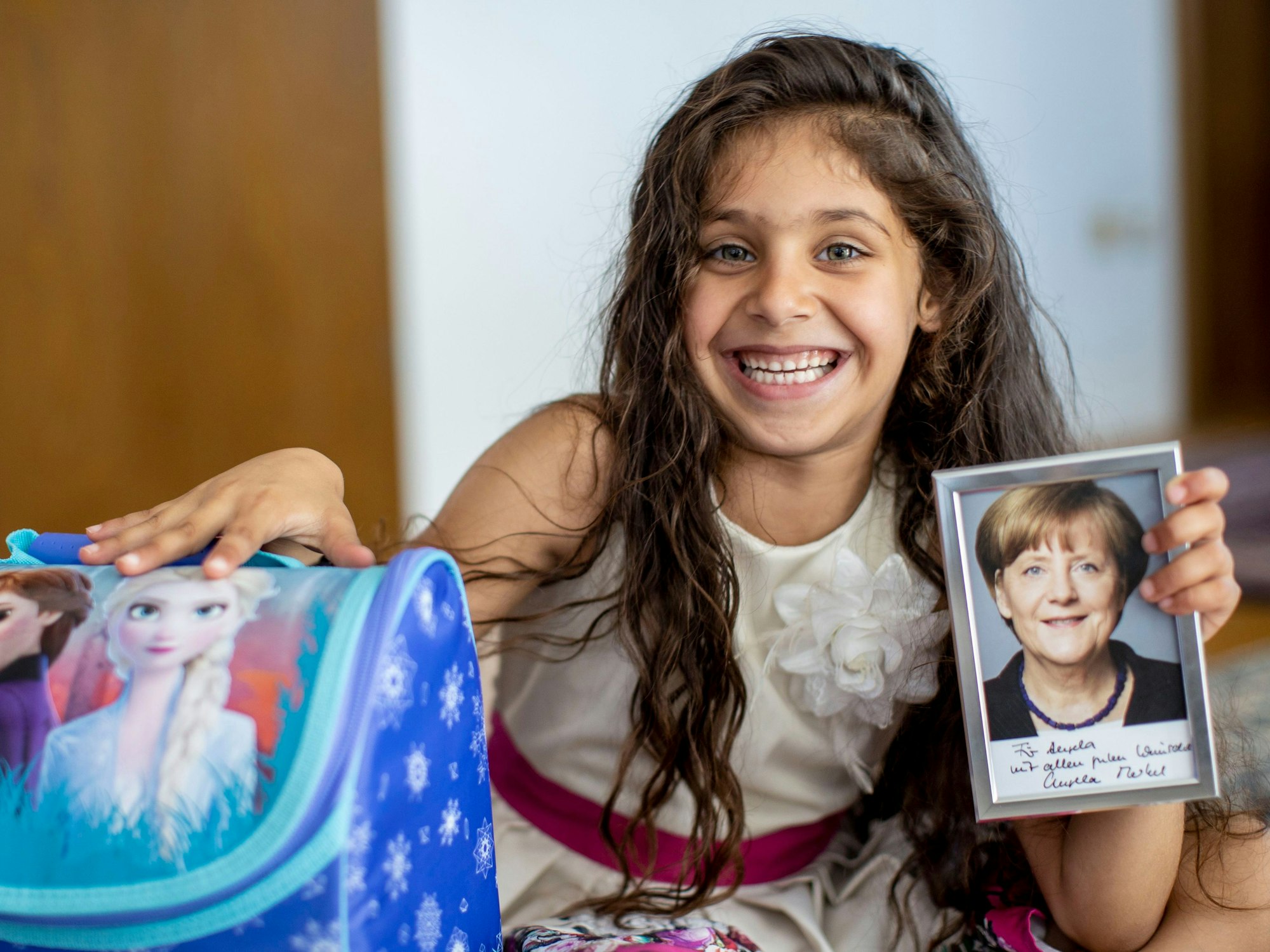 Angela aus Köln hält ein Foto von Angela Merkel in die Kamera, das ihr zur Einschulung zugeschickt wurde.