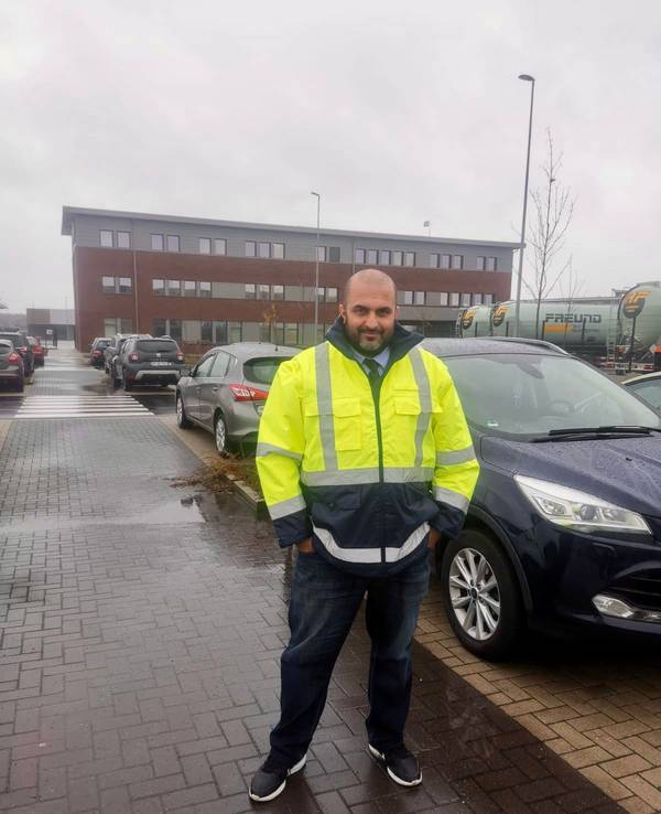 Omar Ali Khalil steht vor einem Auto und lächelt in die Kamera.