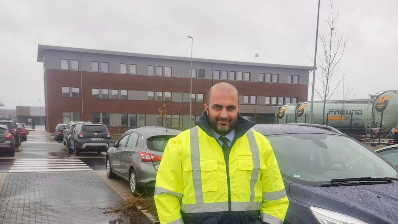 Omar Ali Khalil steht vor einem Auto und lächelt in die Kamera.