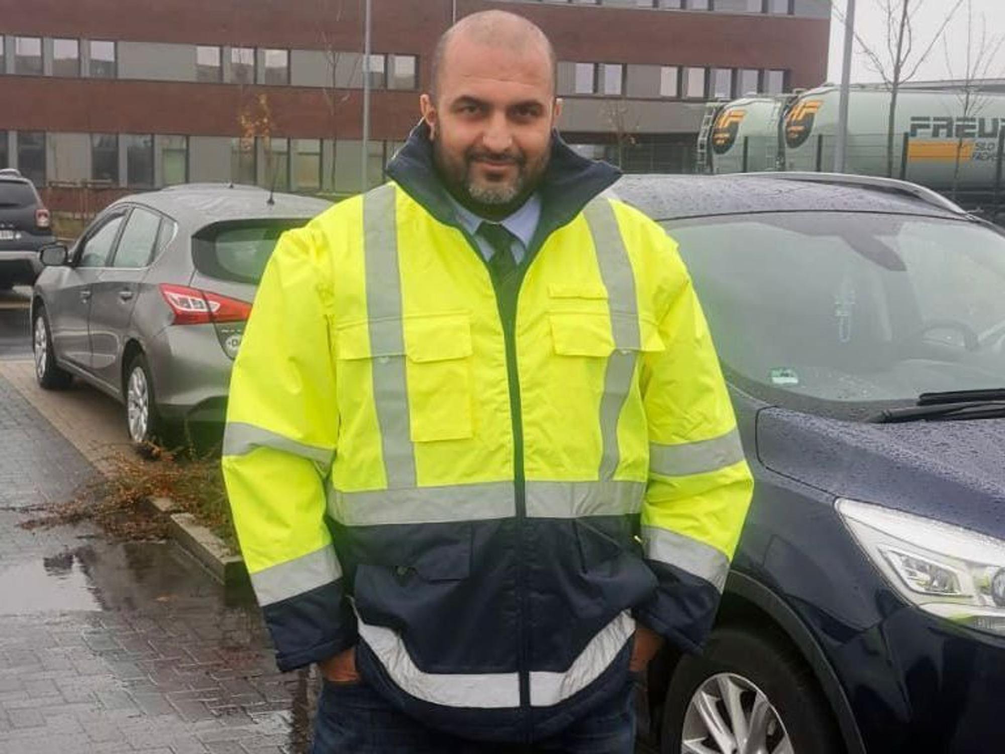 Omar Ali Khalil steht vor einem Auto und lächelt in die Kamera.