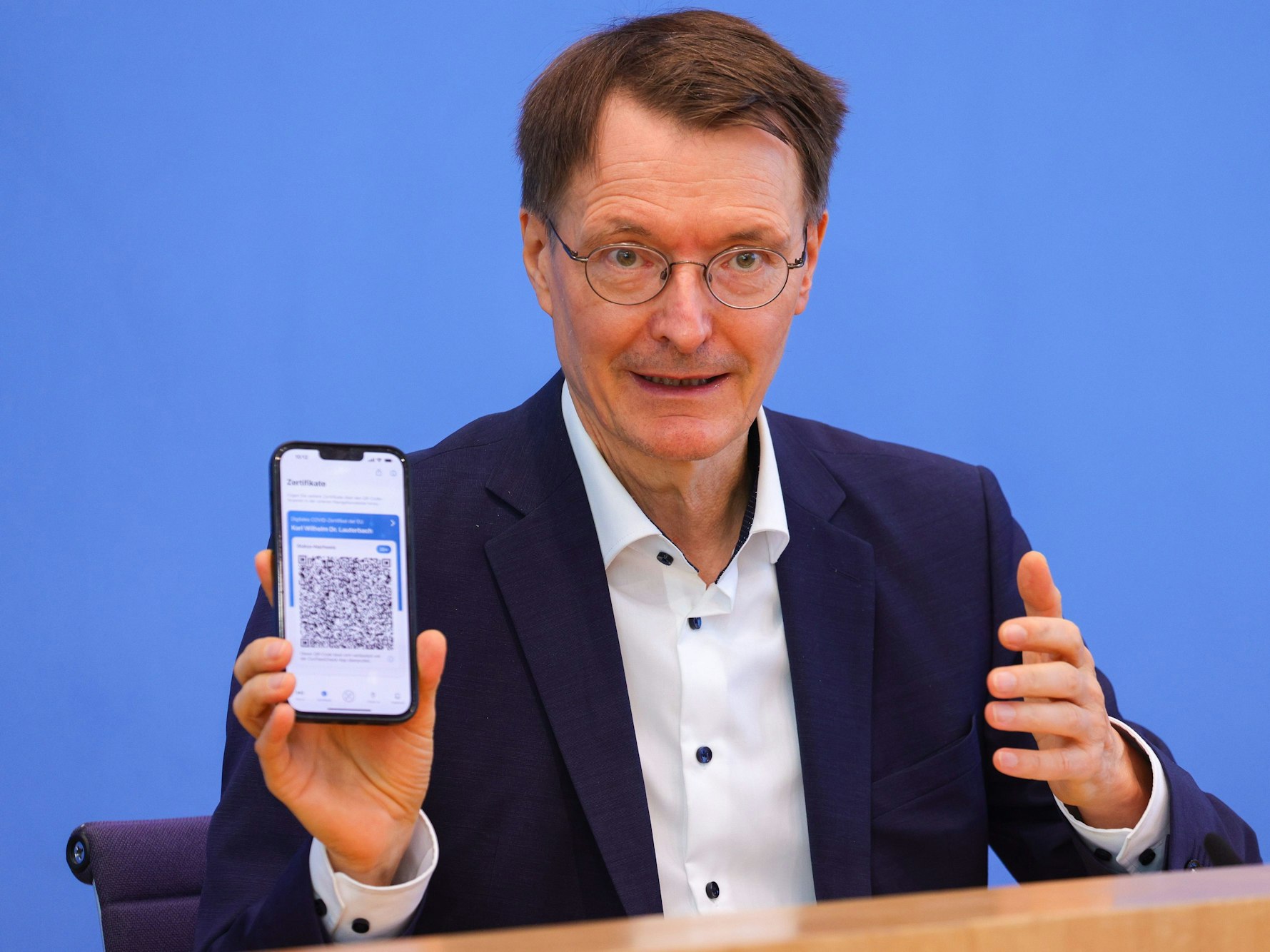 Bundesgesundheitsminister Karl Lauterbach (SPD) zeigt am Freitag (12. August) sein Impfzertifikat in die Kameras. Das bringt ihn nun in Erklärungsnot.