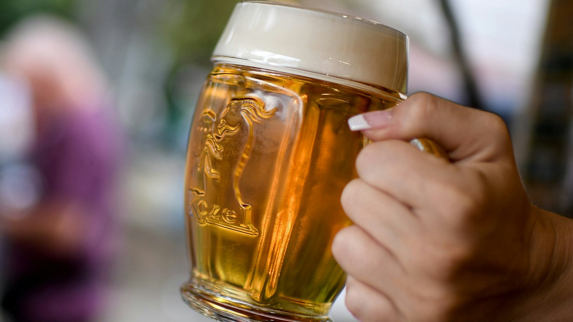 Eine junge Frau schenkt an einem Stand Bier aus.