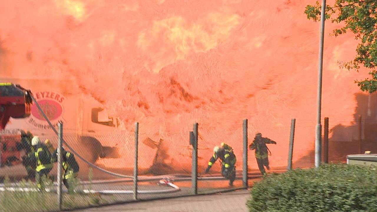 Feuerwehrleute rennen vor einer Flammenwand weg.