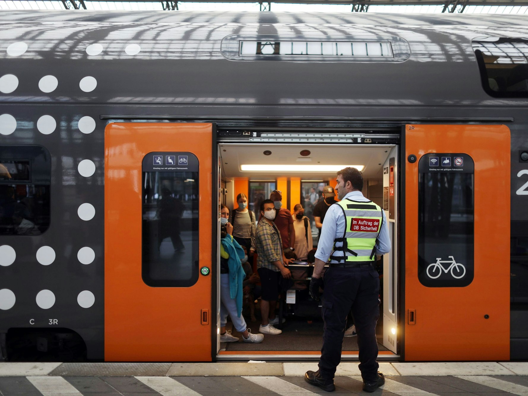 Ein Mann von der DB Sicherheit steht vor einem überfüllten Waggon.