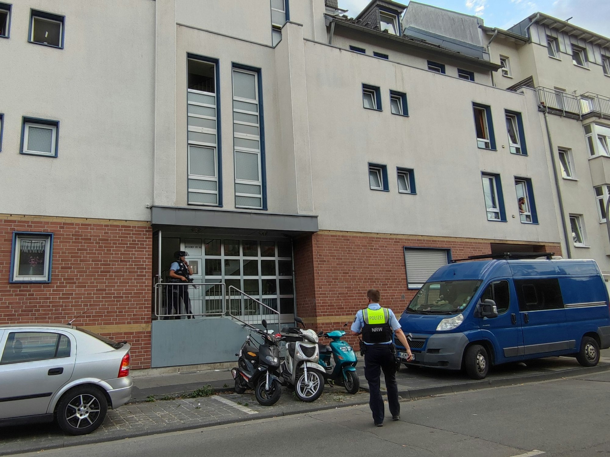 Kräfte der Polizei stehen vor einem Haus in der Gießener Straße in Köln.
