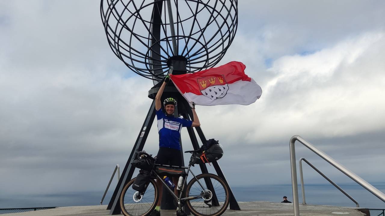 Sebastian Knobloch mit Rad und Köln-Flagge auf der Spenden-Tour