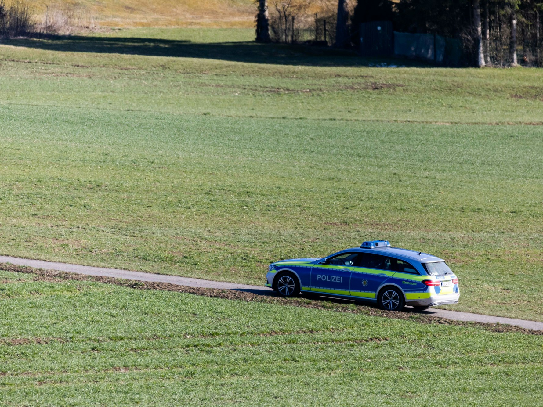 Ein Polizeifahrzeug fährt über einen Feldweg in Baden-Württemberg.