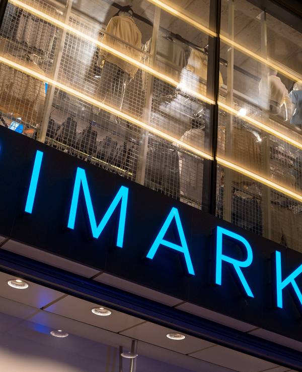 Das Logo des Bekleidungsgeschäfts Primark leuchtet am Abend an der Fassade.