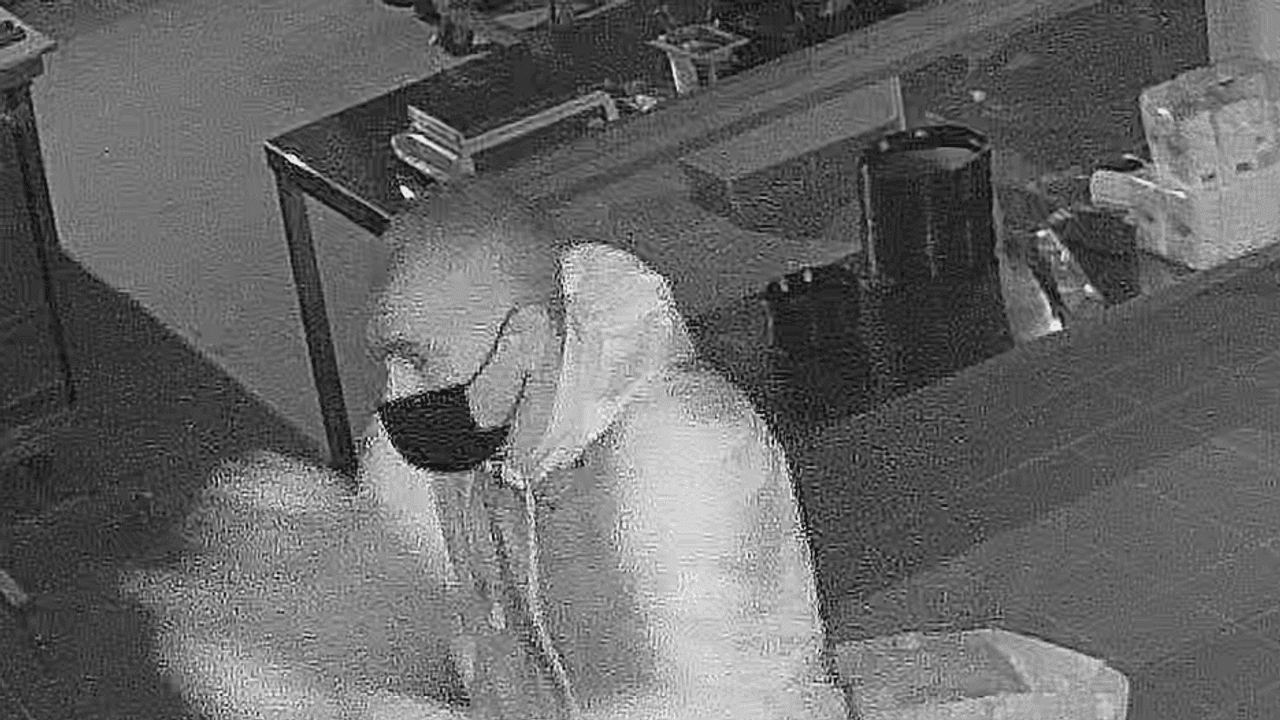 Mann steht in einer Pizzeria und verschüttet eine Flüssigkeit. Nach ihm wird nun öffentlich gefahndet.