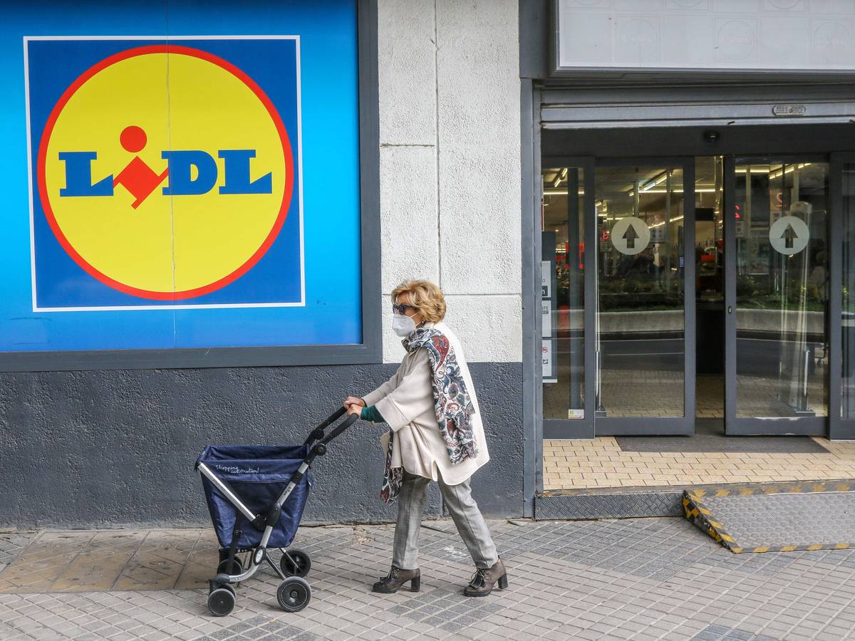 Eine Frau mit Rollator trägt einen Mund-Nasen-Schutz und passiert ein Einkaufsladen von Lidl.